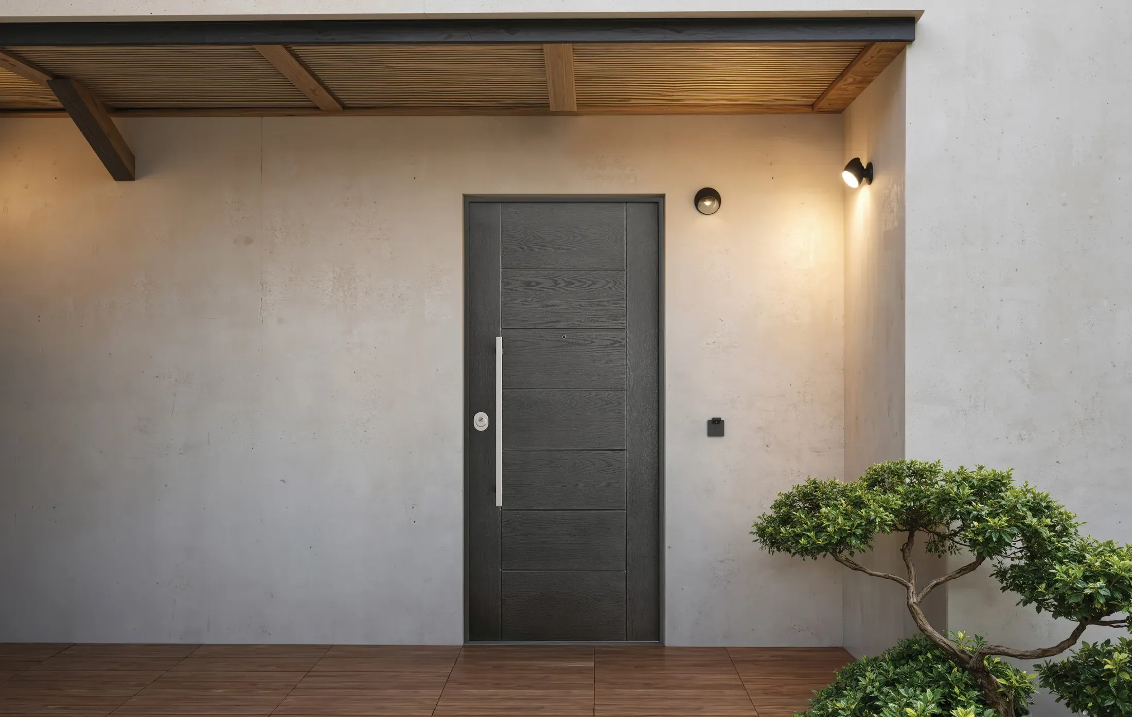 BUNKER Thermoenergy Grado 3 Helios — porche concreto con puerta antracita, bonsái y lámpara cobre